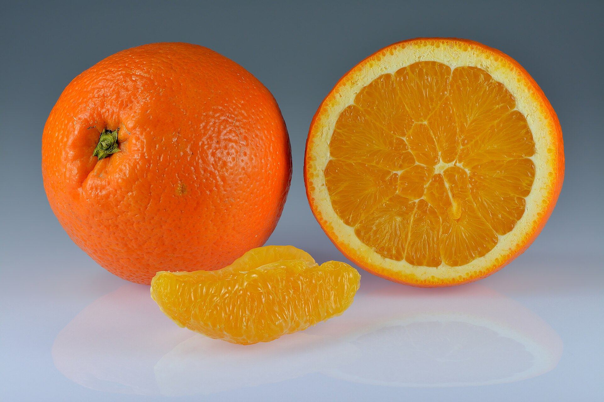 Whole sweet orange, a halved orange, and a peeled segment